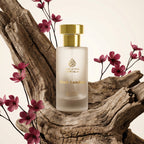 Perfume bottle with gold cap on a wooden log with pink flowers